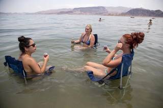 From left, Subrina Madrid, Sarah Hudak, Jennifer, Shackelford, all of North Las Vegas, sit in the shallow waters along Boulder Beach at Lake Mead, Saturday, June 29, 2013. The three planned to spend the day at the lake to escape the heat in Las Vegas, where Saturday's daytime high was expected to reach 117 degrees.